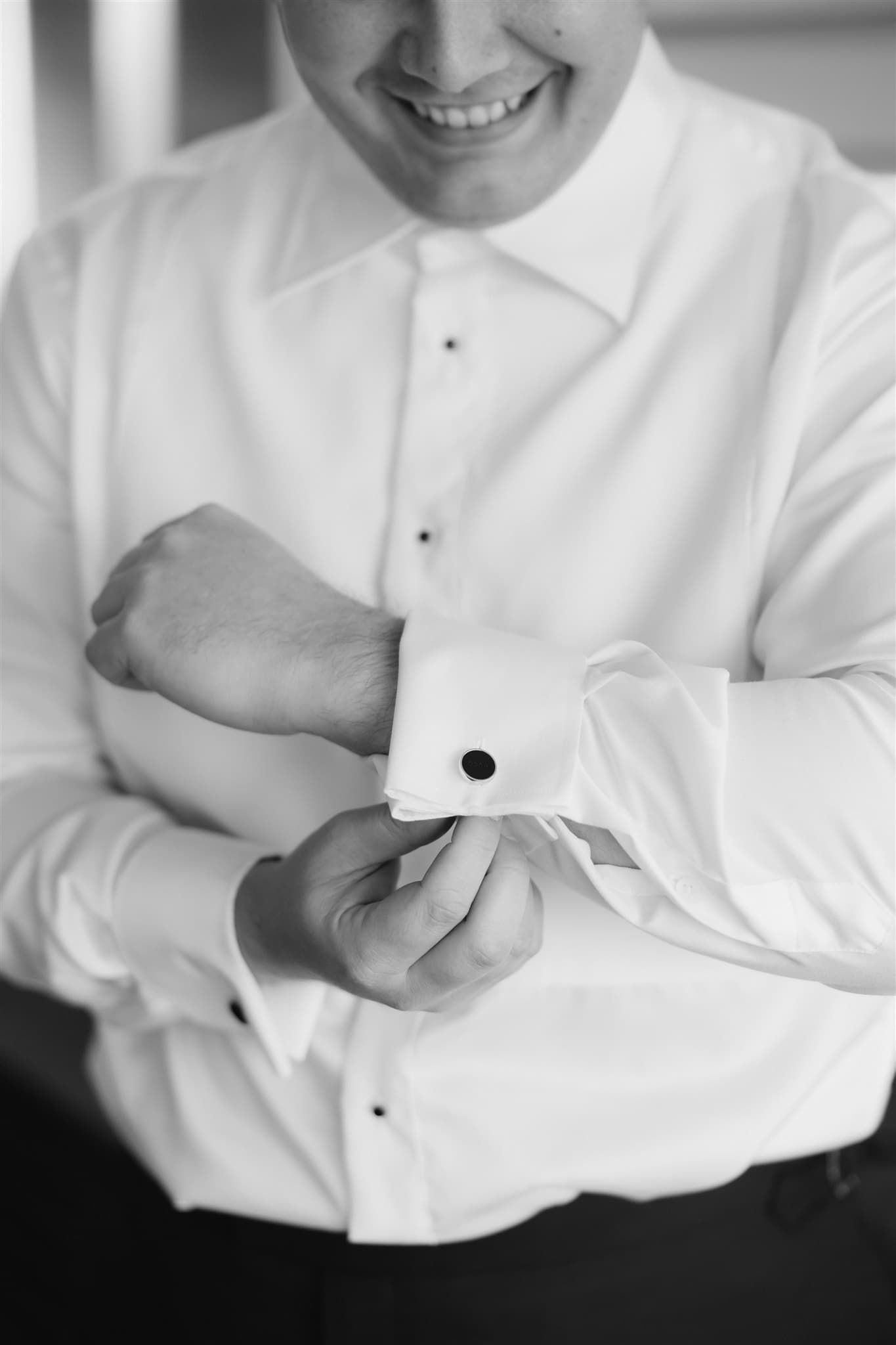 Groom buttoning up shirt