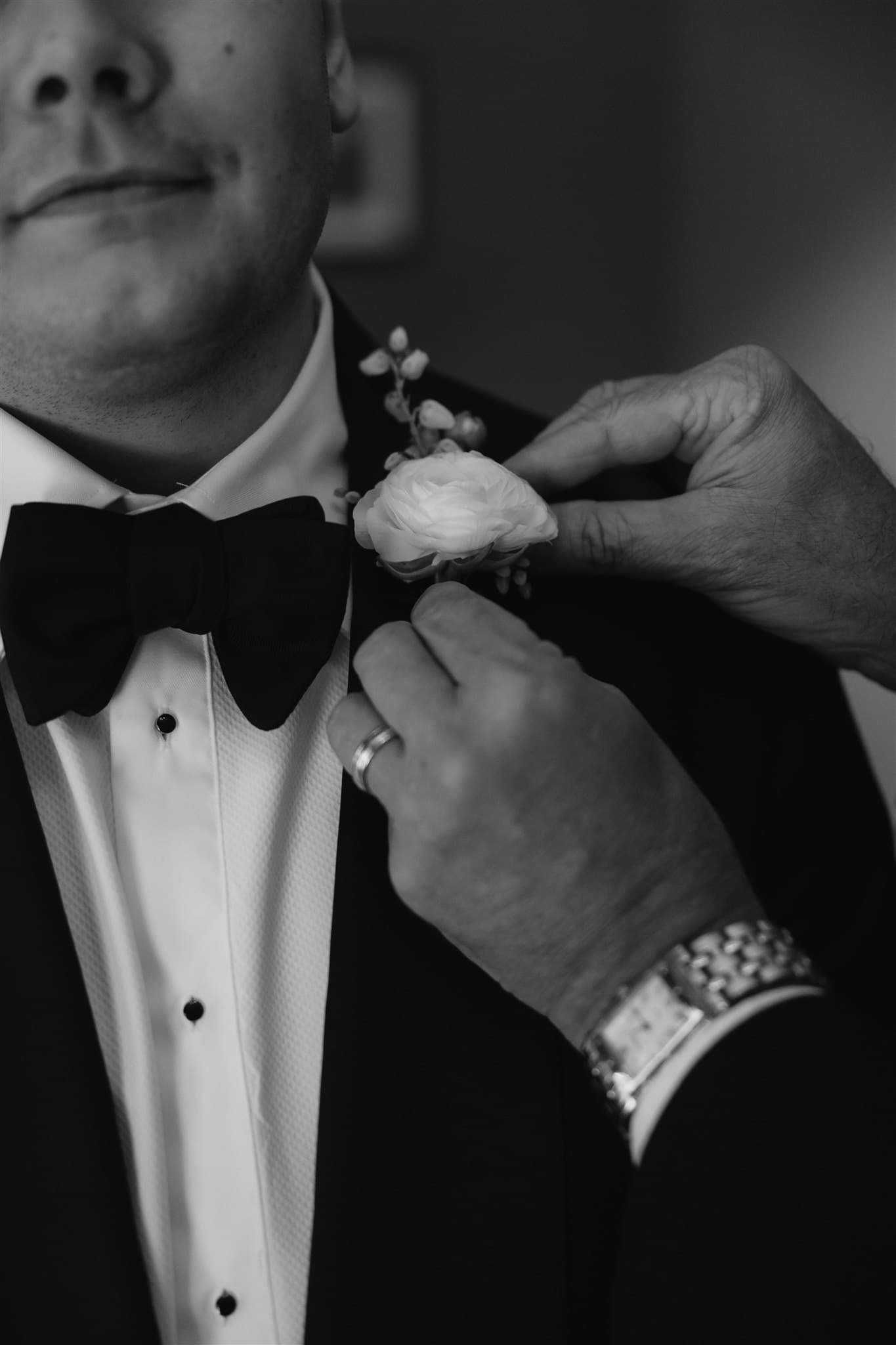 Man pinning boutonniere onto suit jacket