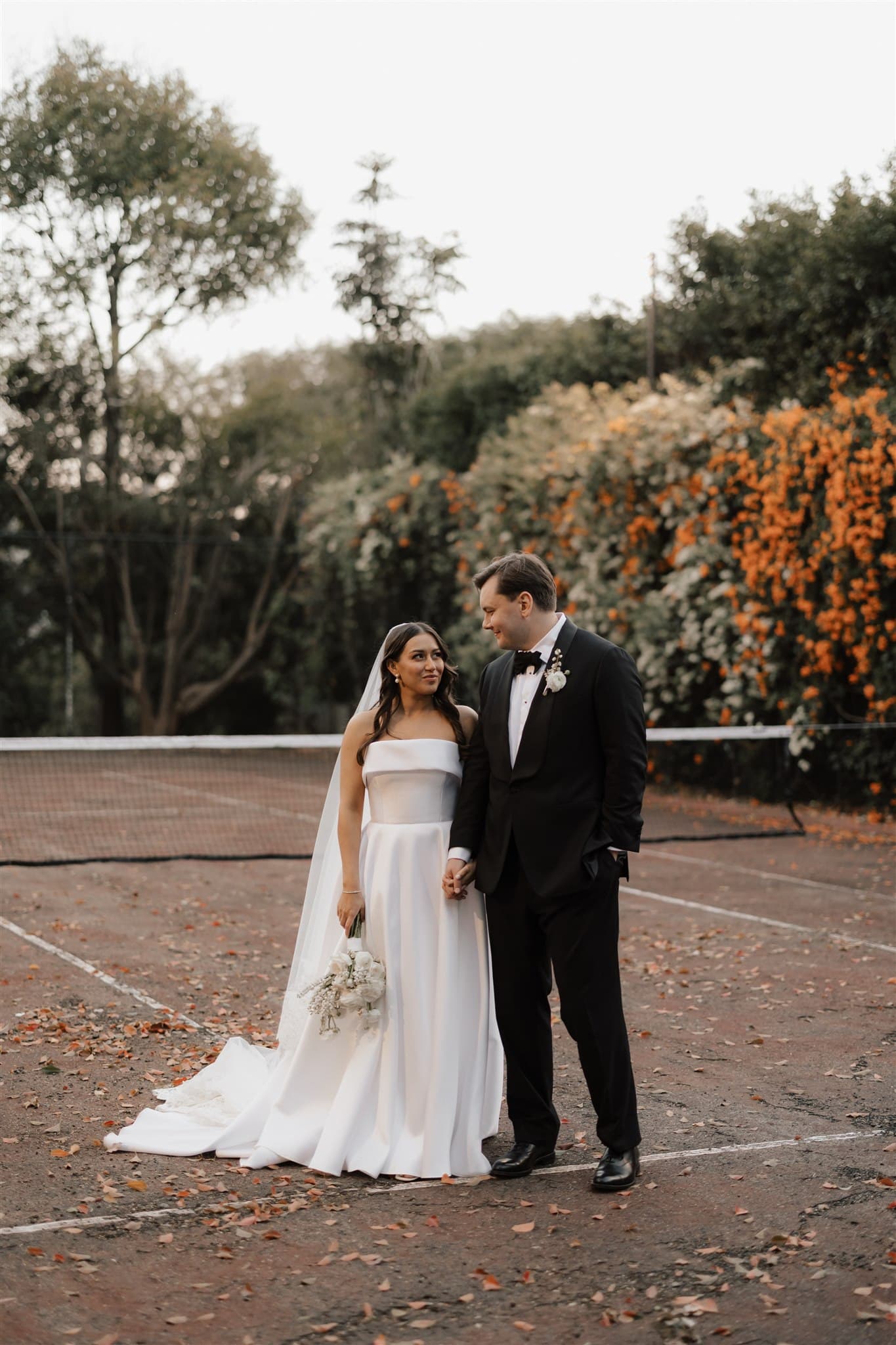 Bride and groom standing on tennis court