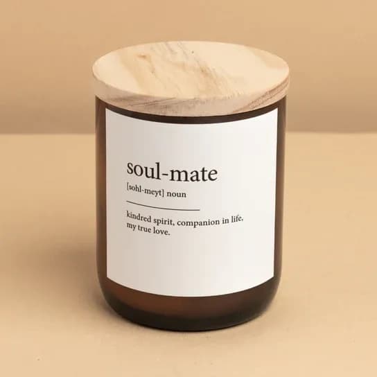 A brown candle with a light wooden lid sits against a beige background. The label reads "soul-mate [sohl-meyt] noun - kindred spirit, companion in life, my true love.