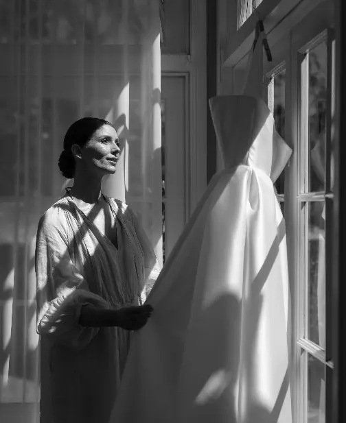 Bride looks at dress in the window light