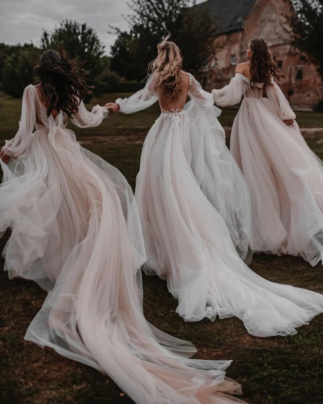 3 brides wearing dresses with long flowing trains