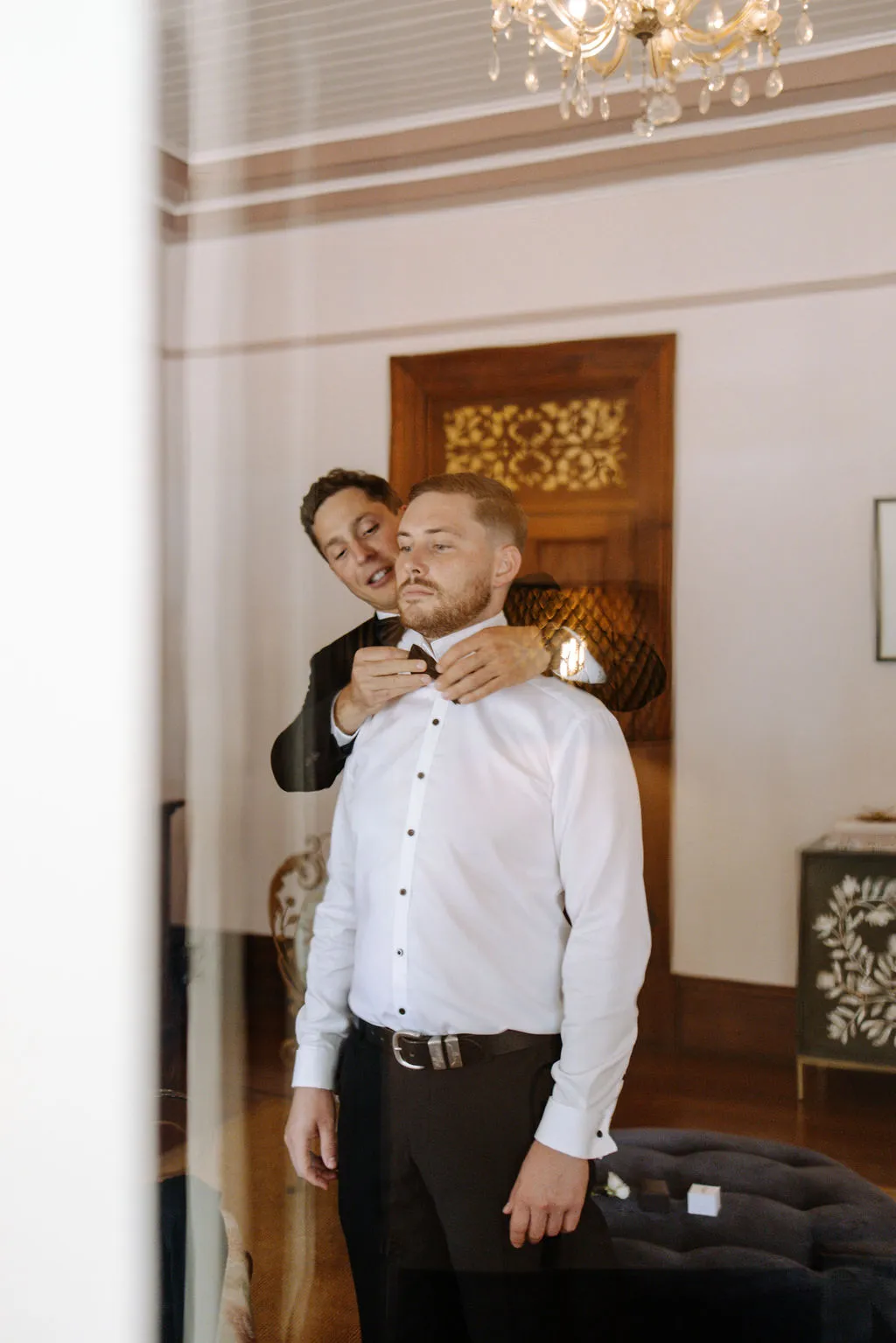 Groomsmen putting on grooms bowtie