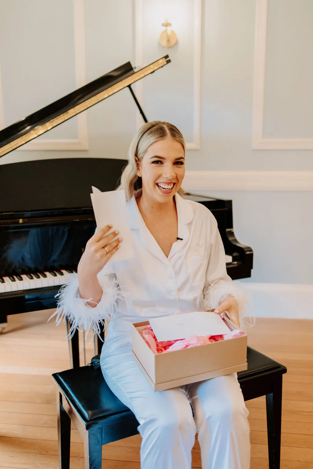 Bride sitting on piano chair holding a box