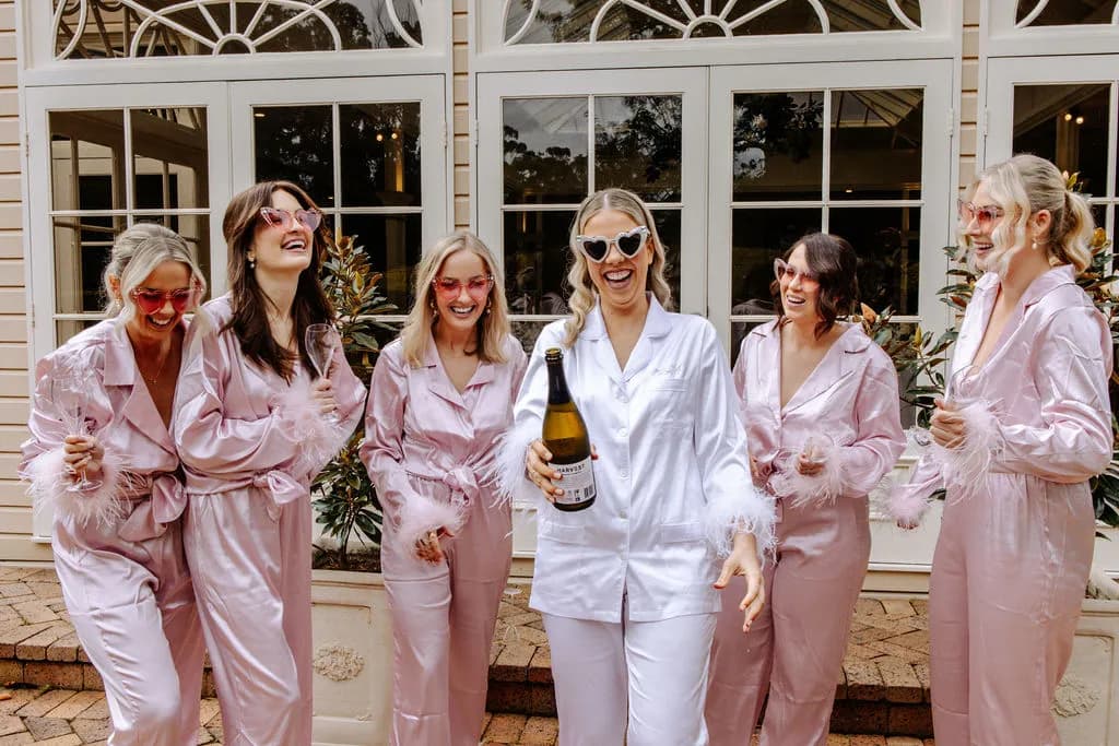 Bride popping champagne with bridesmaids