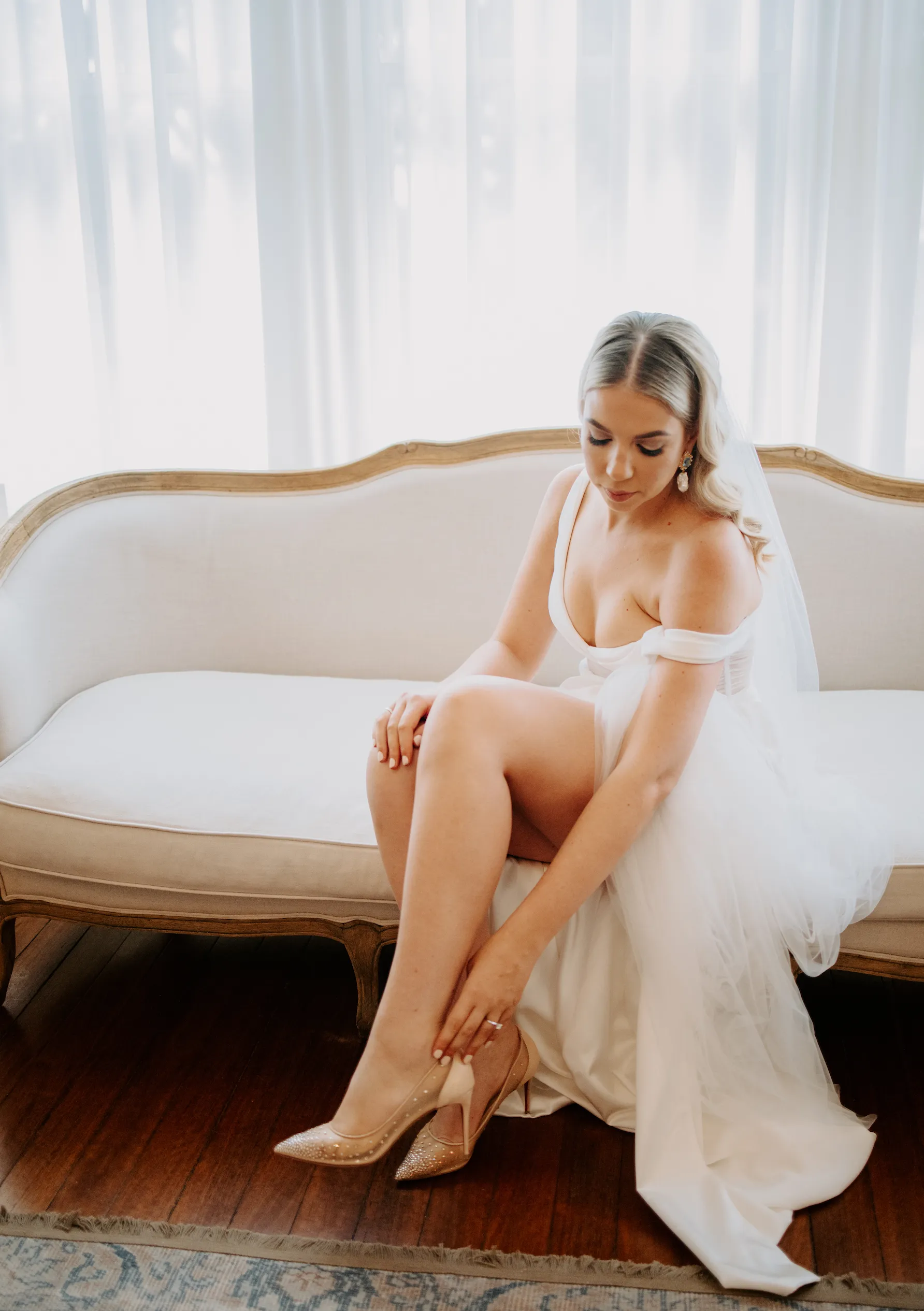 Bride sitting on couch putting on shoes