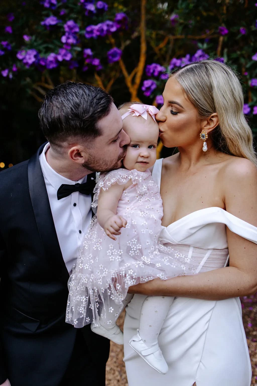 Bride and groom kissing daughter