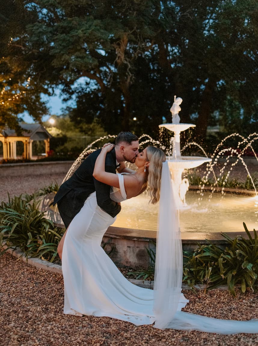 Bride and groom kissing in front of fountain