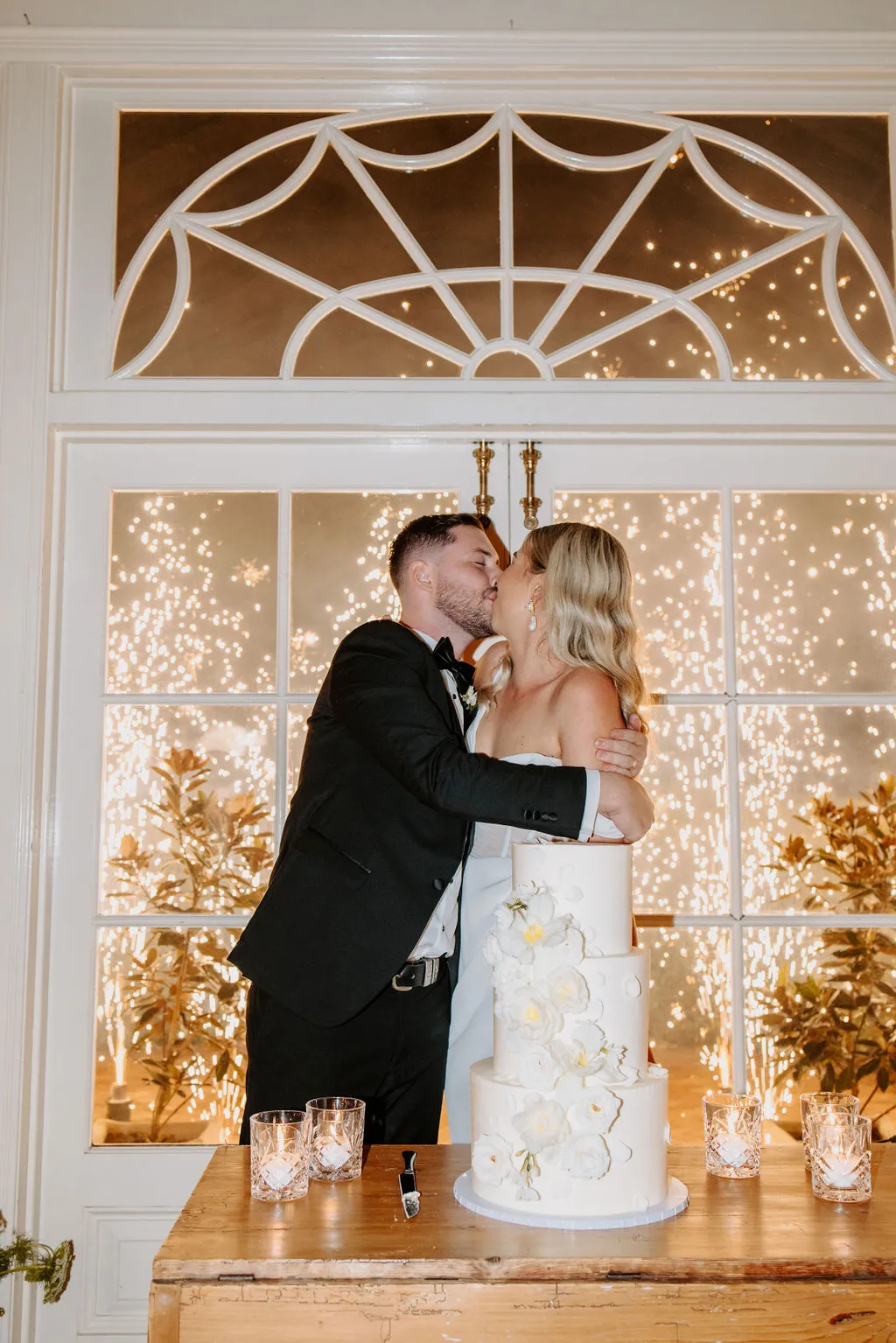 Bride and groom cutting cake in front of fireworks