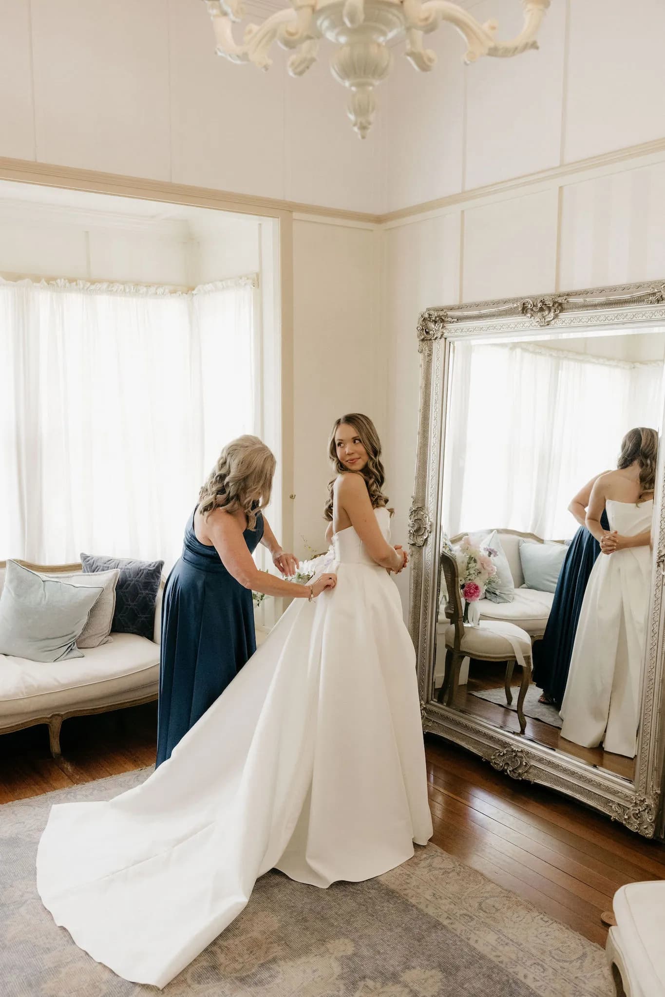 Mother of bride helping put on wedding dress