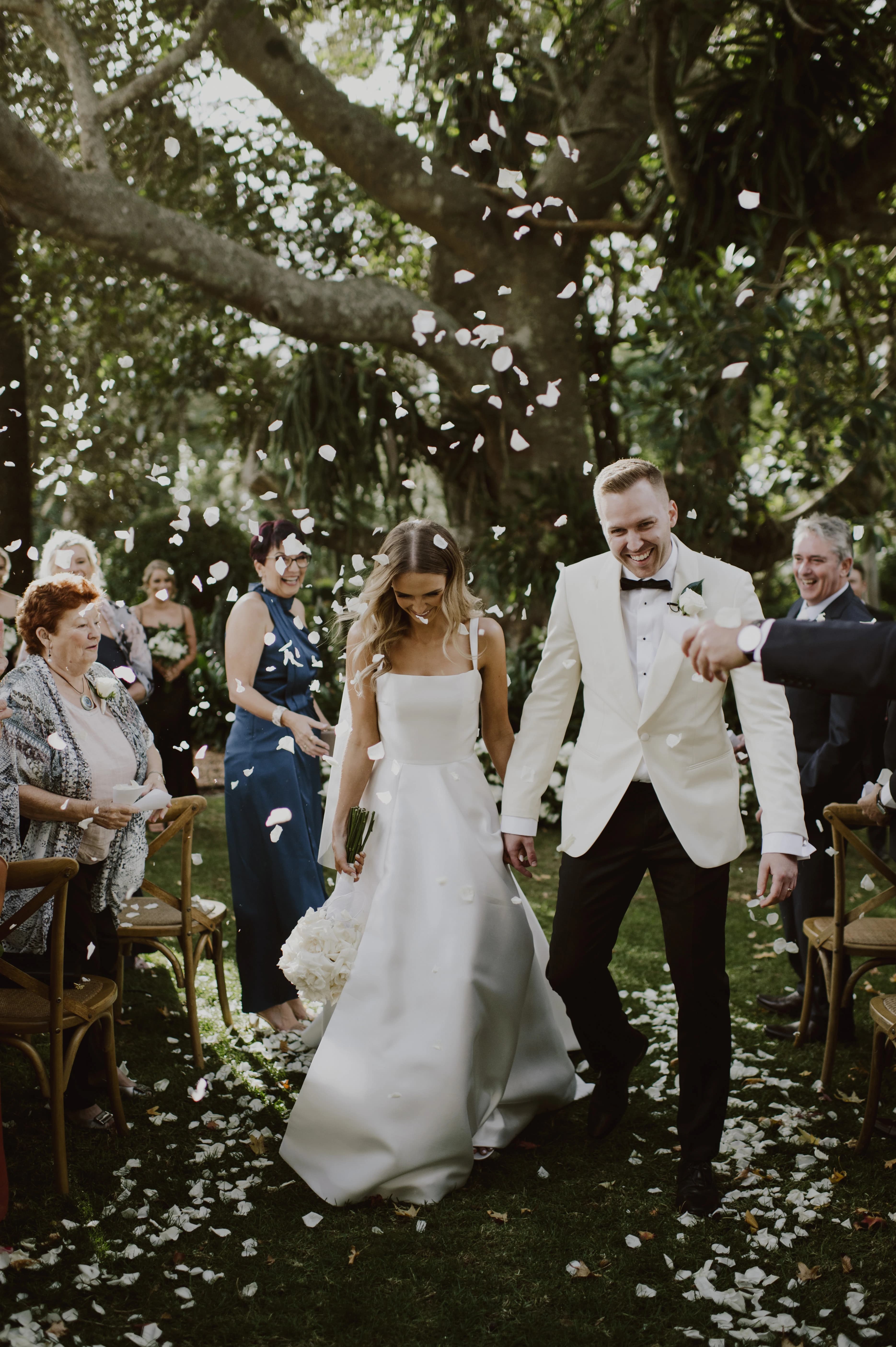 Petals are thown at a couple as they walk down the aisle