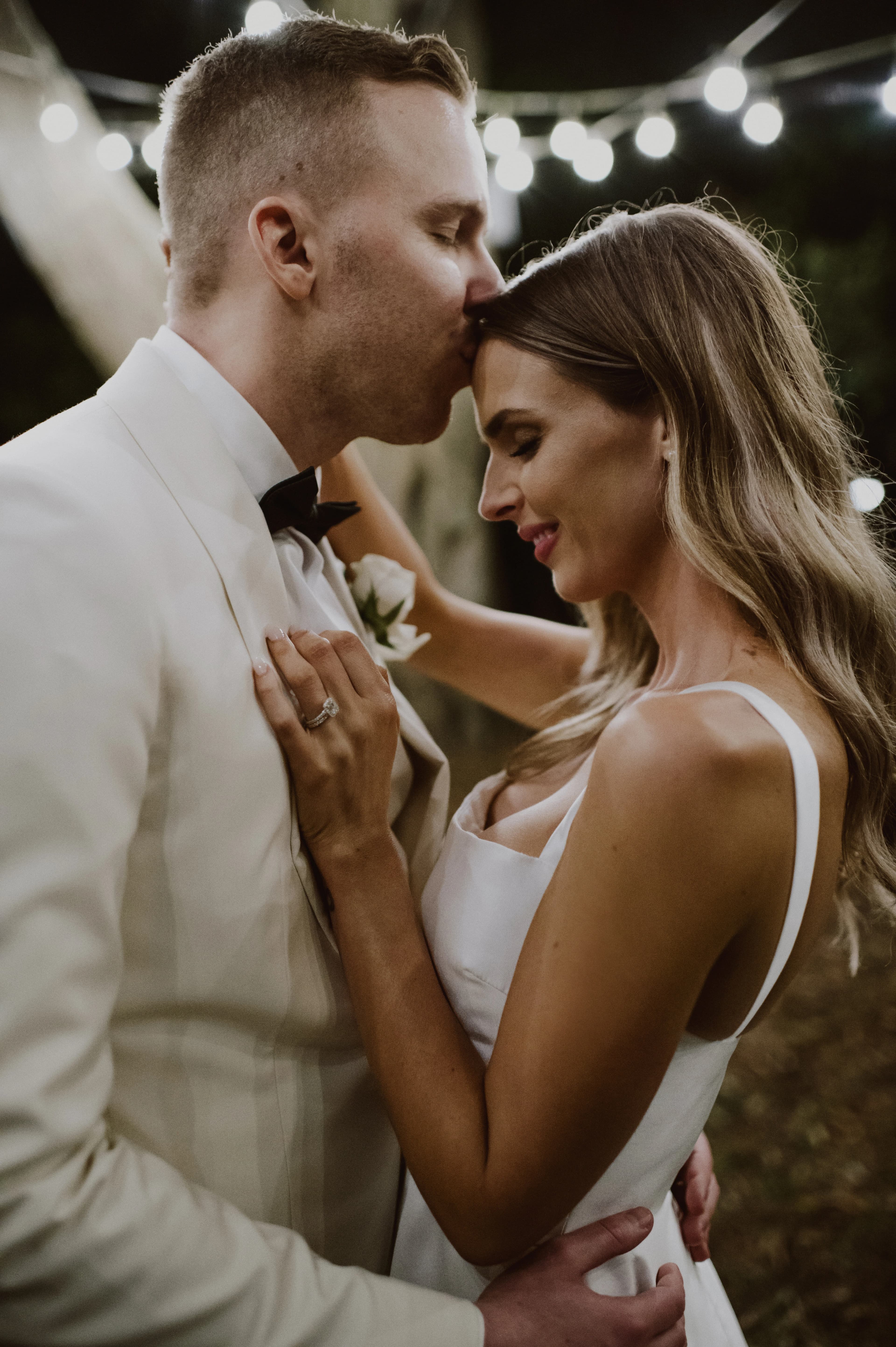 close up of couple dancing under fairy lights