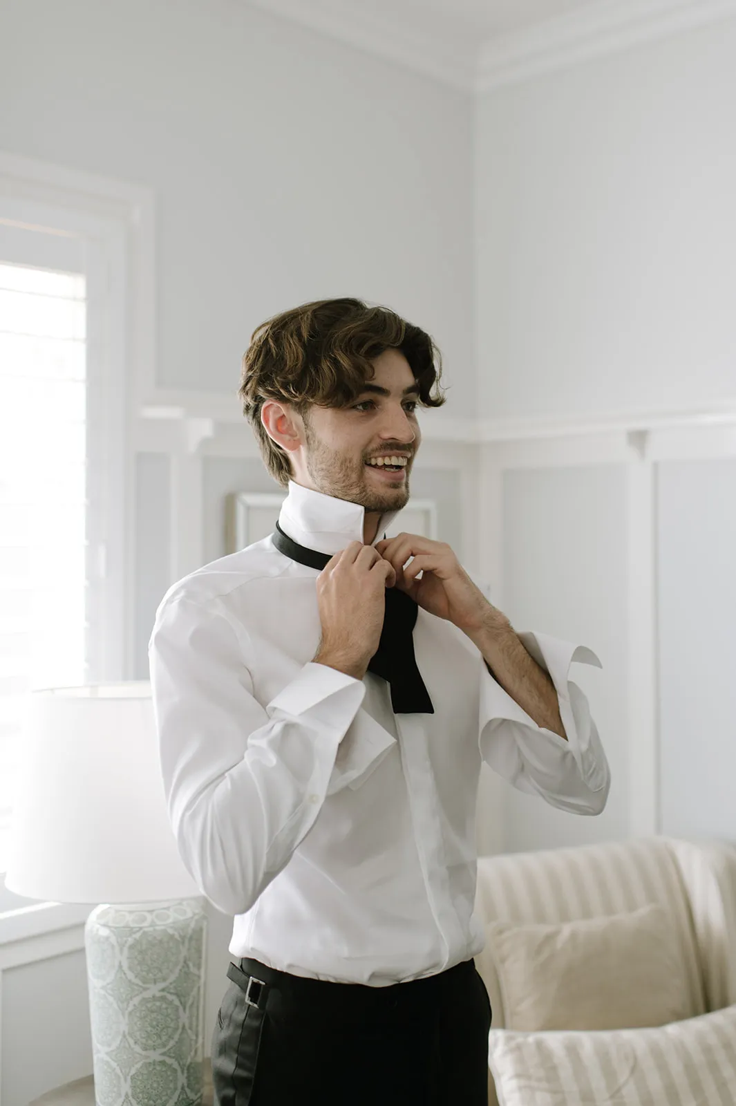 a man getting ready for a wedding tying his bow tie