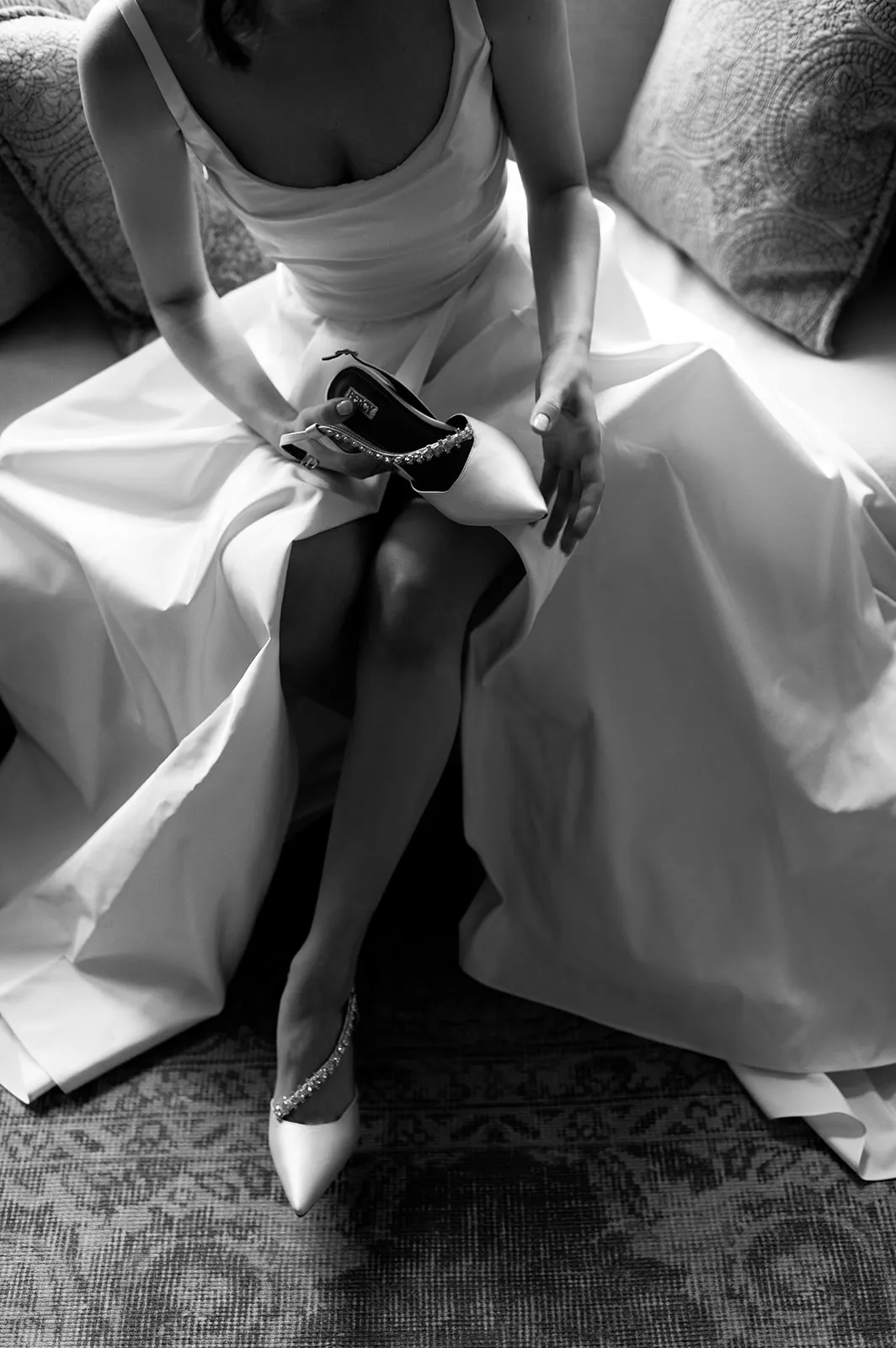 a bride on her wedding day sitting down in her beautiful dress and putting on her wedding shoes