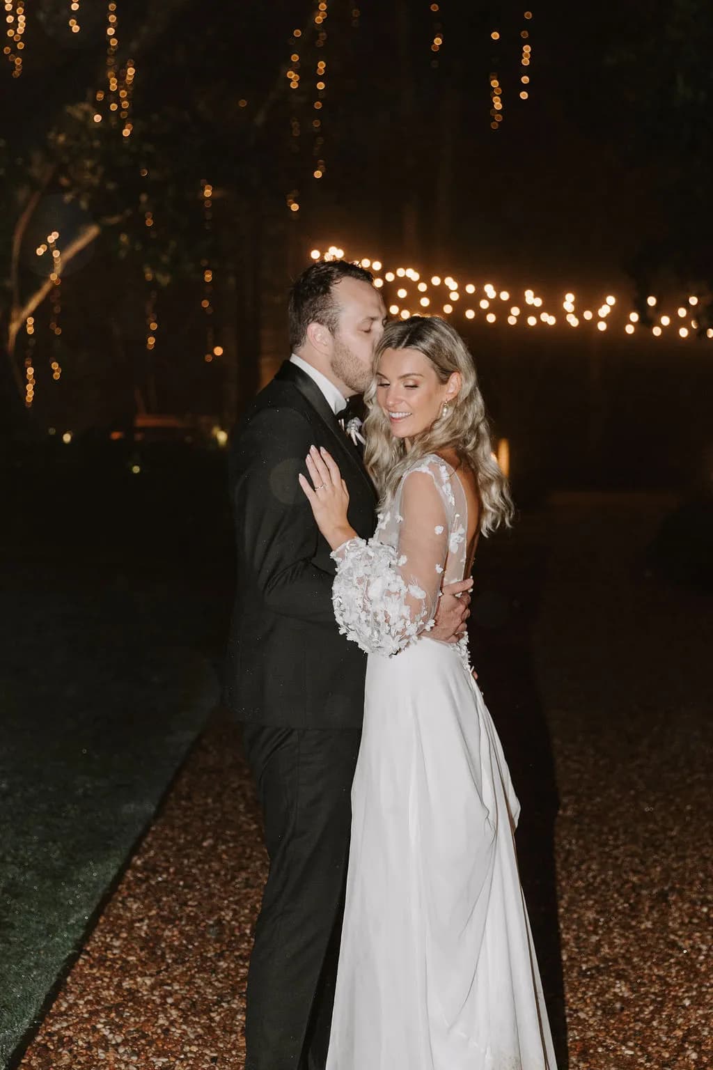 Bride and groom outside standing under festoon lights