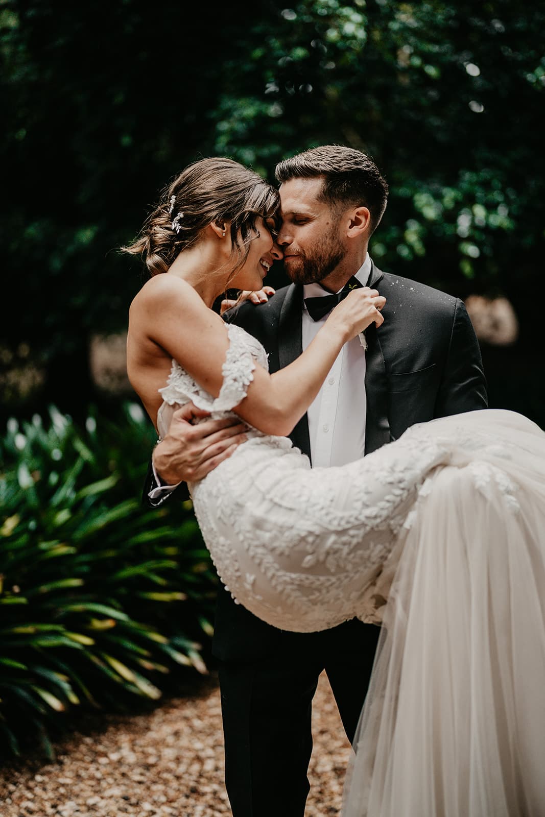 Groom carrying bride down driveway
