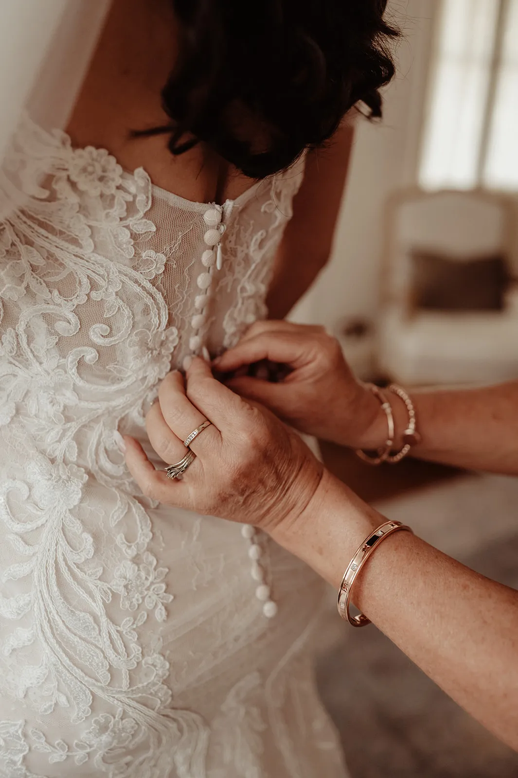 Mother of the bride doing wedding dress buttons up