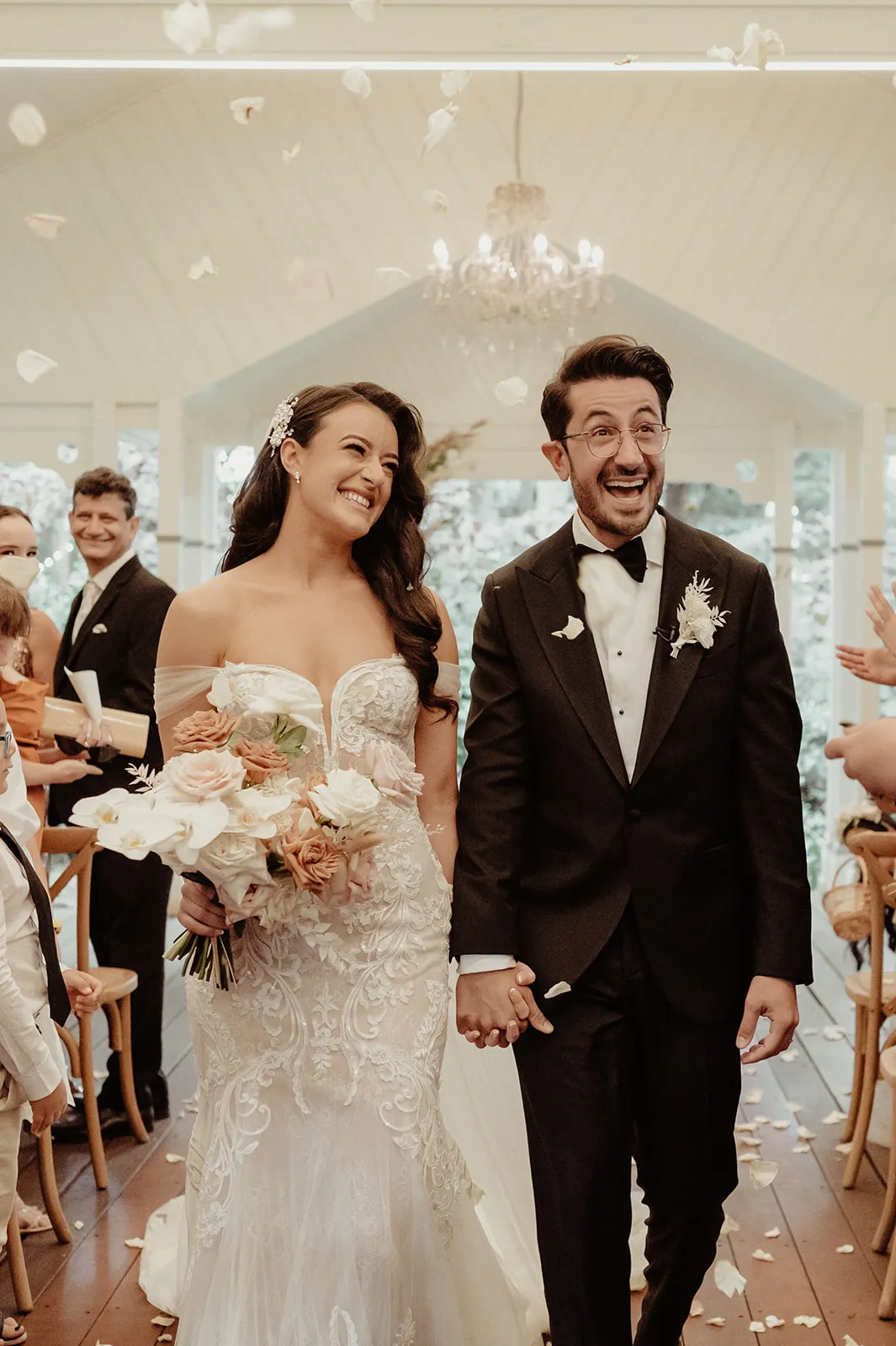 Bride and groom walking down the aisle with rose petals behind them