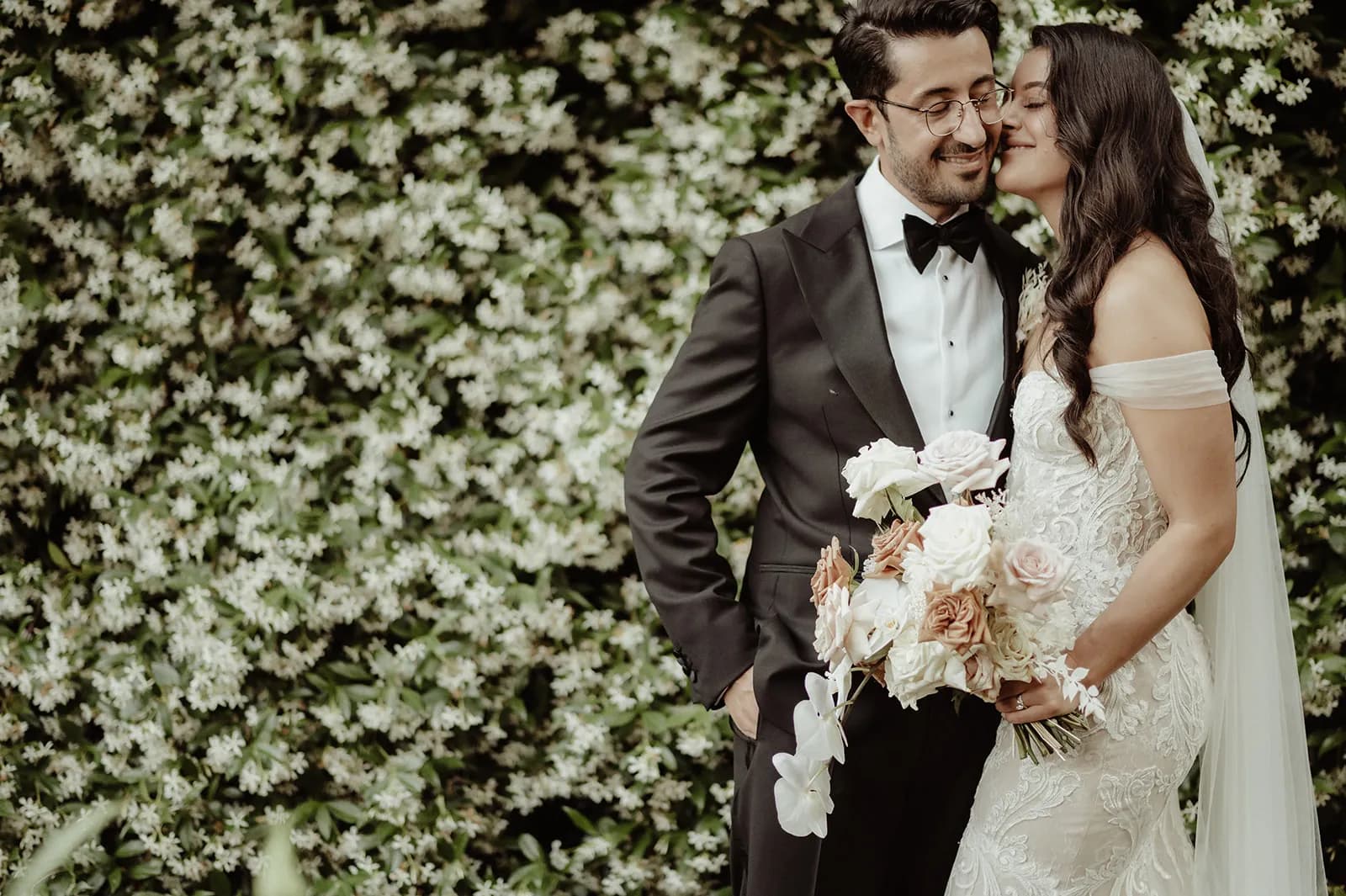 Bride and groom standing in front of Jasmine vine