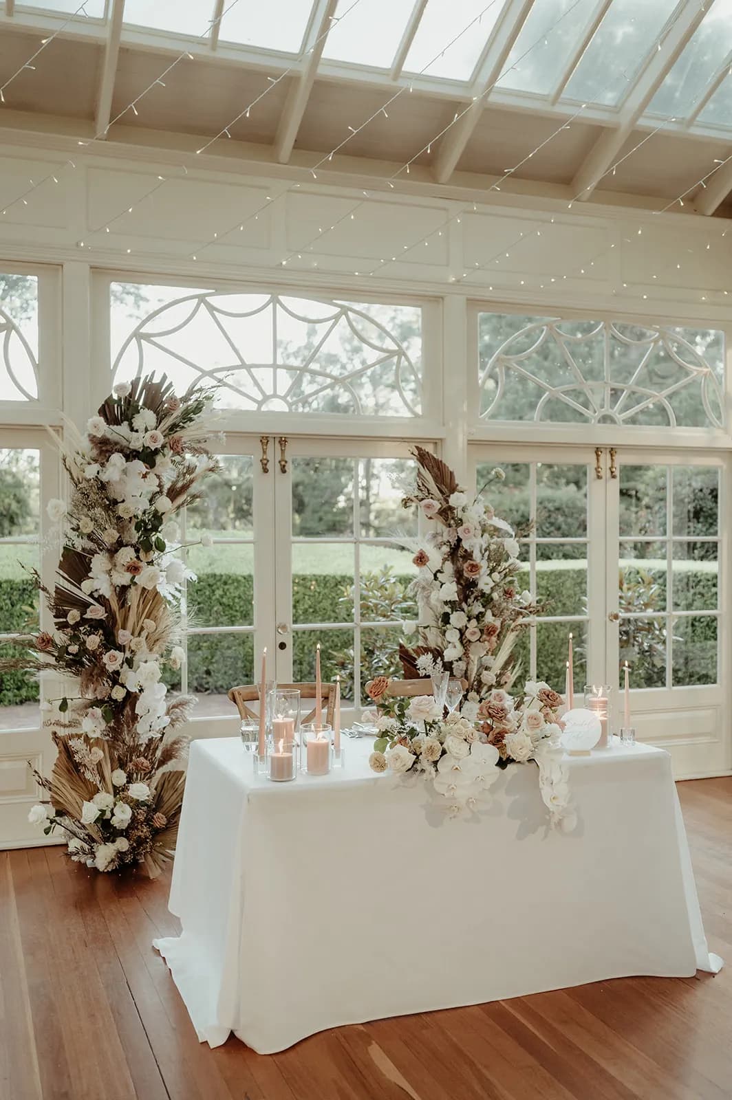 Bride and groom wedding table with flowers behind