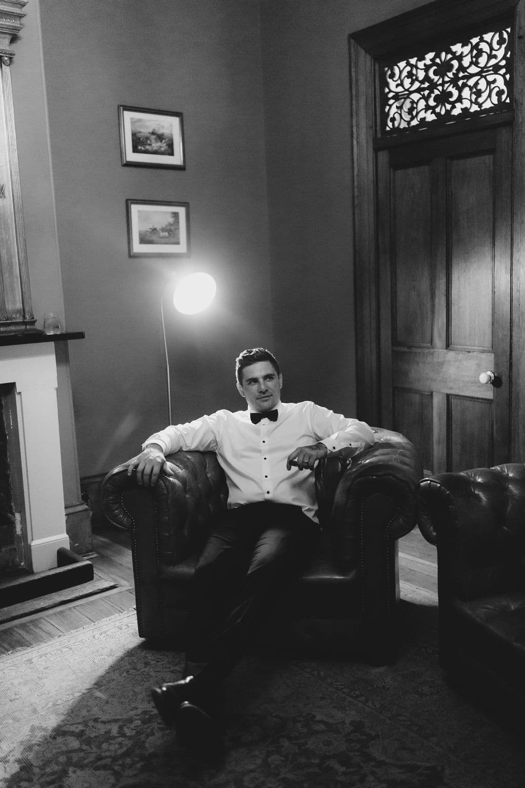 a man in a wedding suit sitting on a comfortable leather chair