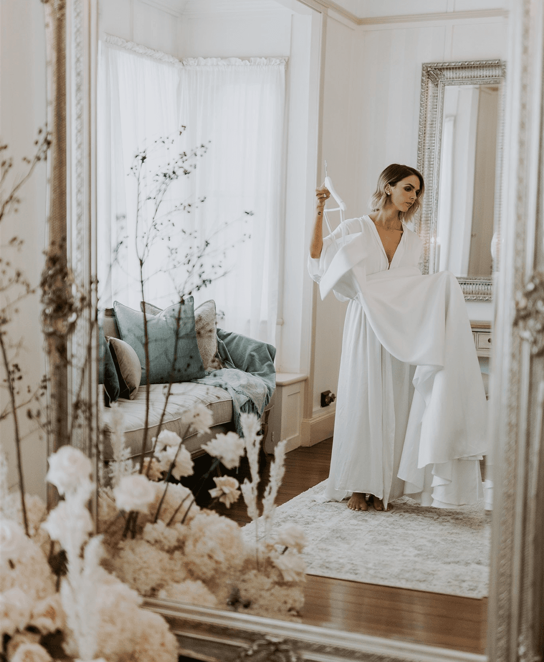 A bride in a white dress admiring her reflection in a mirror.