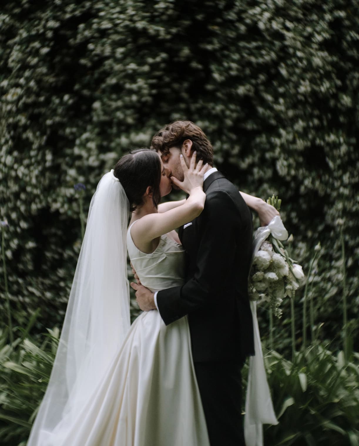 Couple kiss in front of star jasmine vine