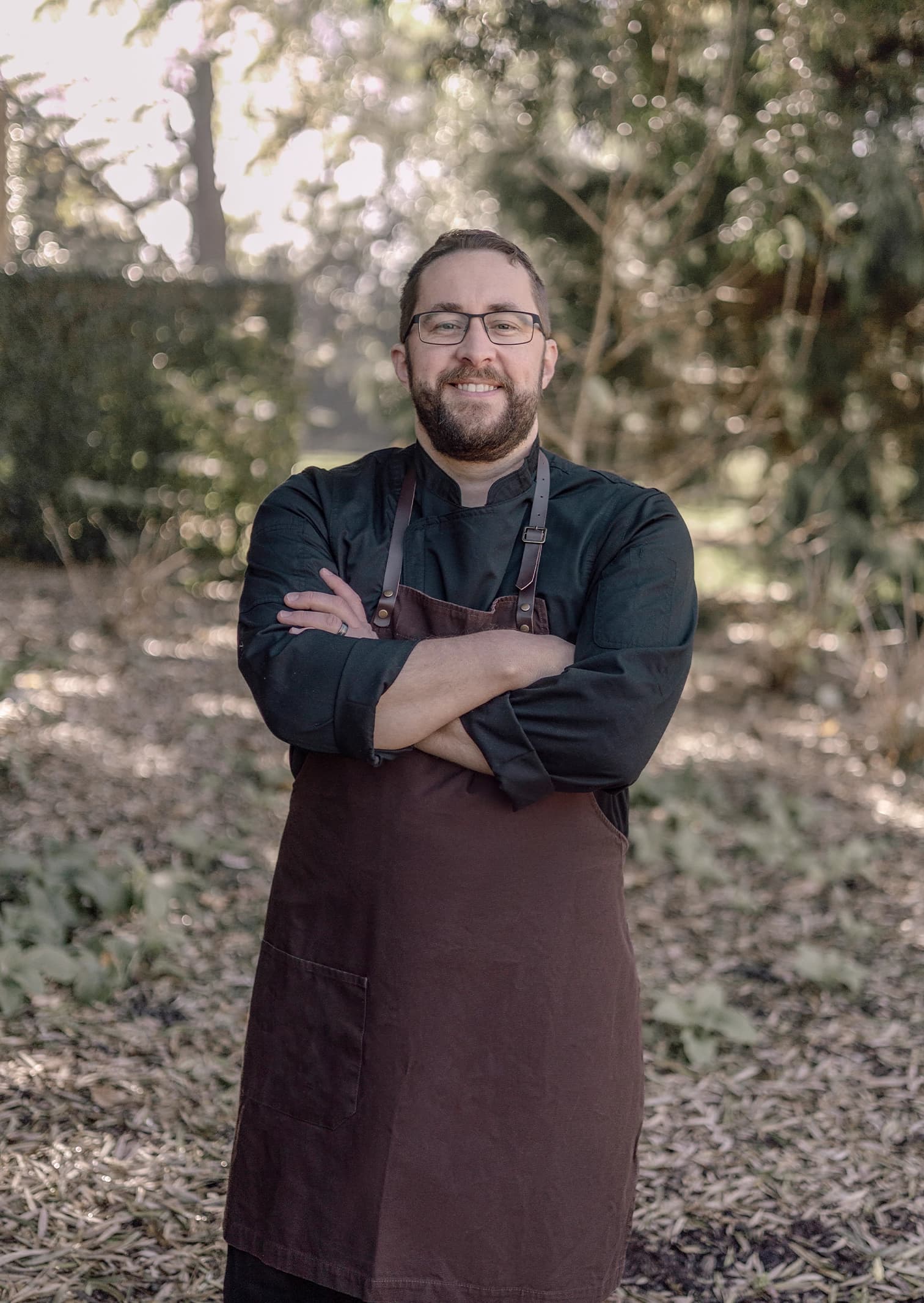 Chef Robbie smiles at the camera with arms crossed