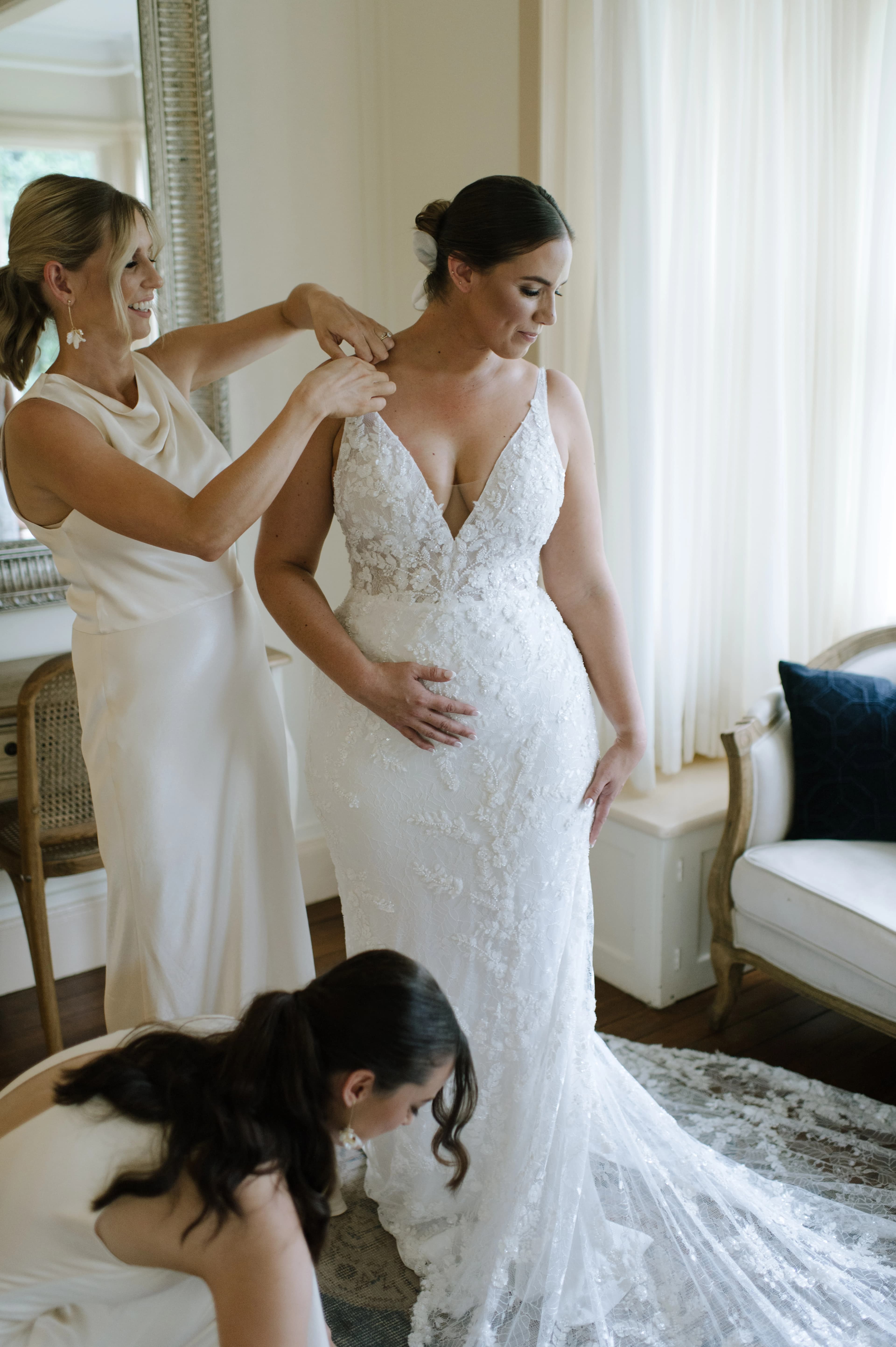 A standing bride preparing for her wedding with her bridesmaids