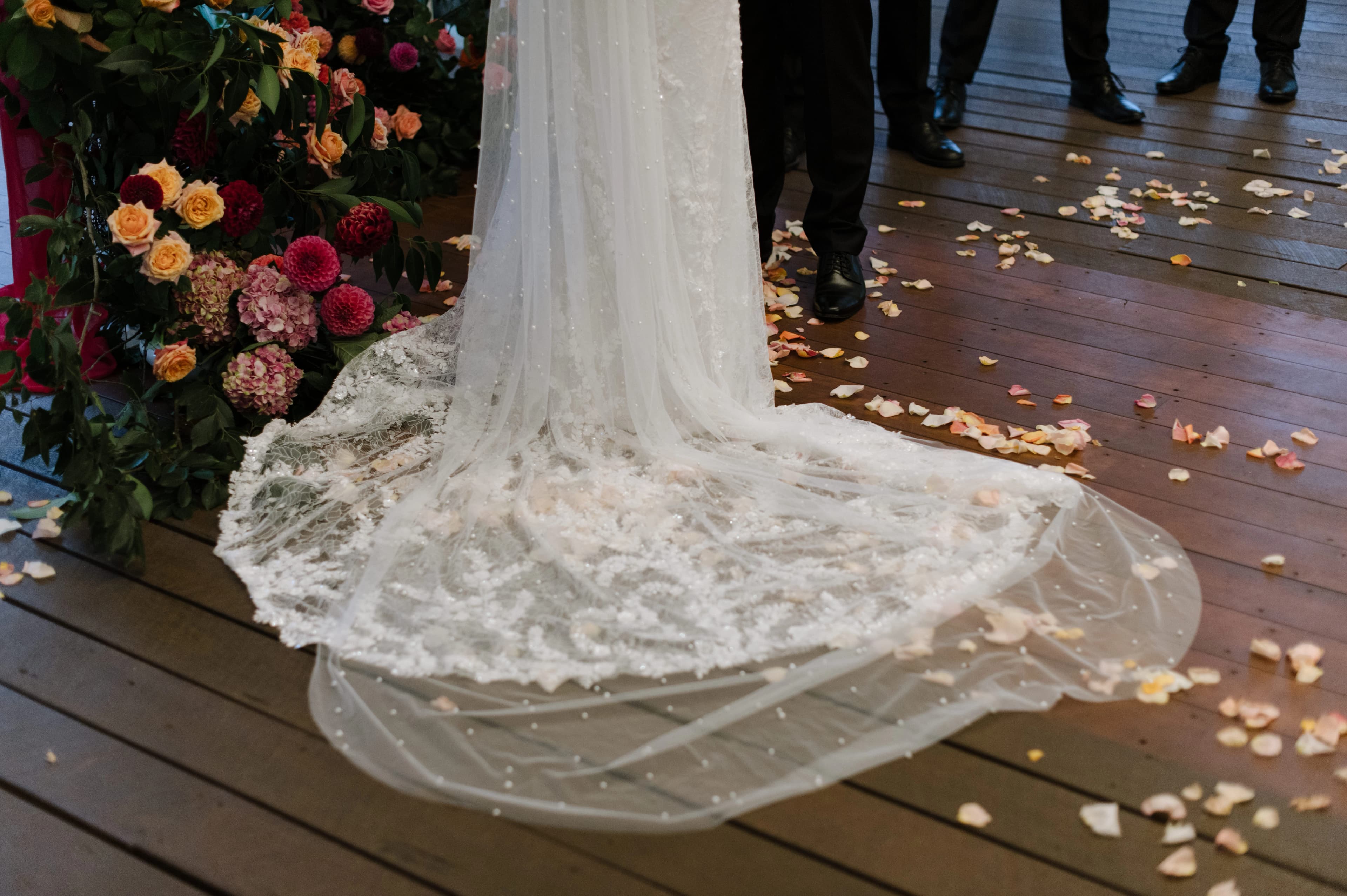 Elegant wedding dress with floral arrangements and guests witnessing the couple's vows.