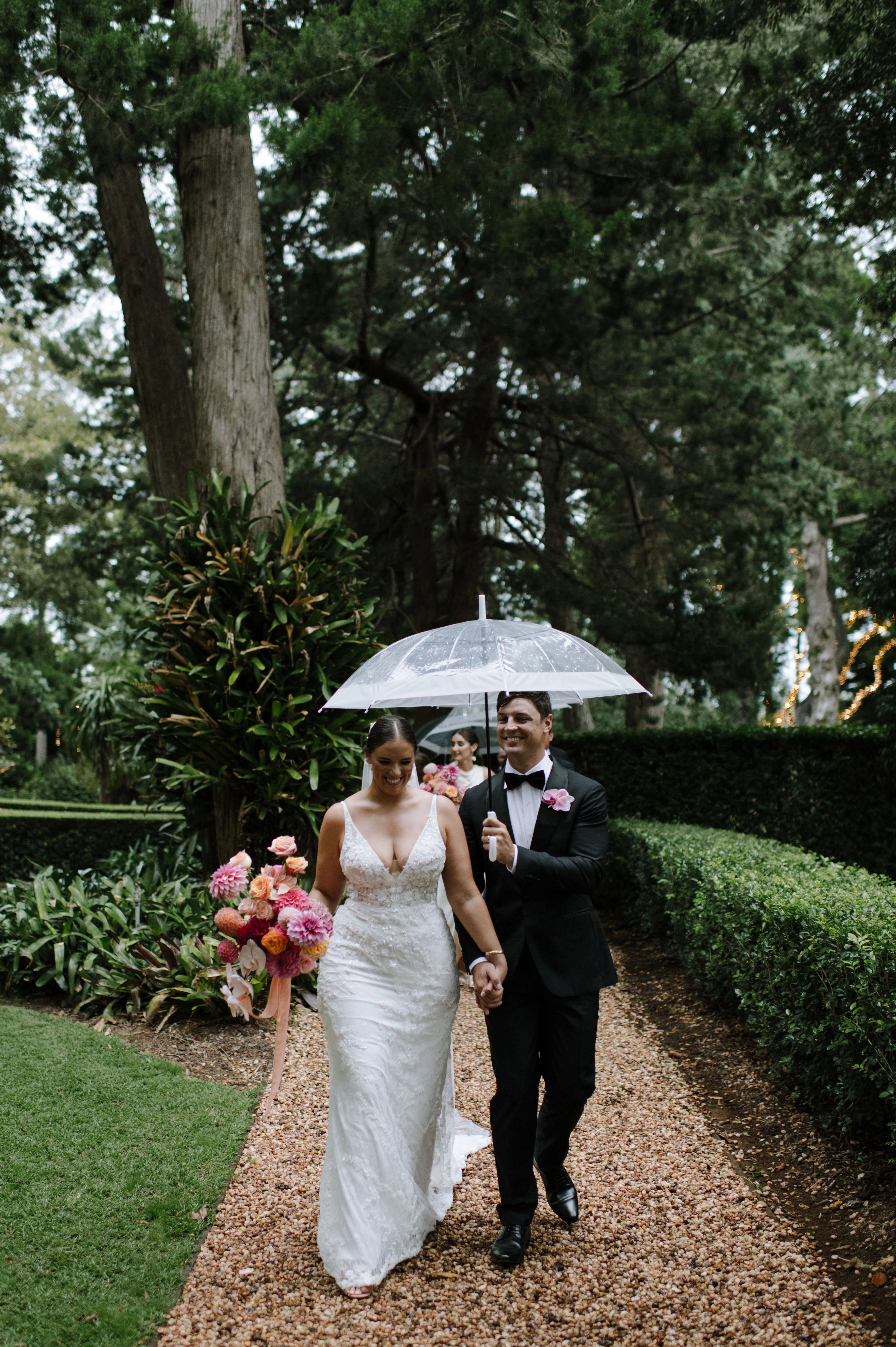 A romantic wedding moment captured featuring a couple under an umbrella in a beautiful greeny foresty scene.